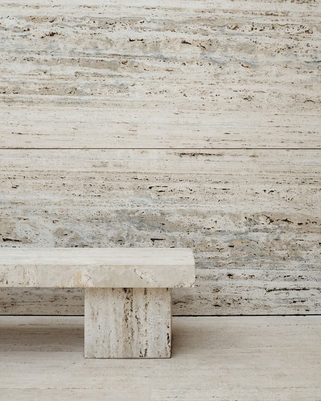 Banc de travertin devant un mur de pierre.